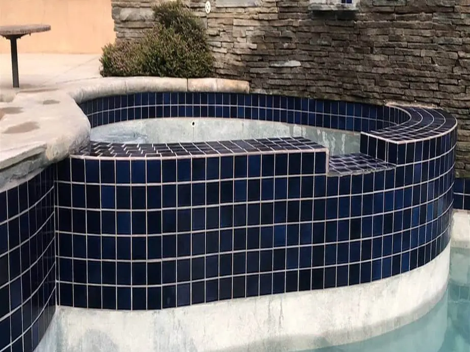 Raised spa with deep blue waterline tile and clear water after cleaning